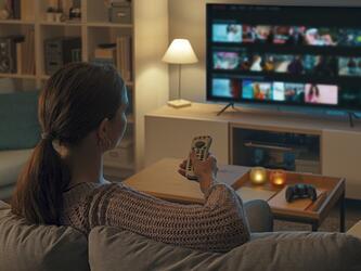 Woman sitting on couch watching TV media audience viewing television dec 25_crop